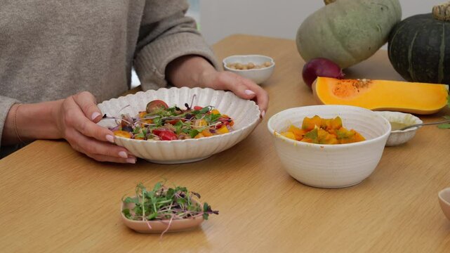 Cloes up shot of female hands placing a plate with a salad on the wooden table