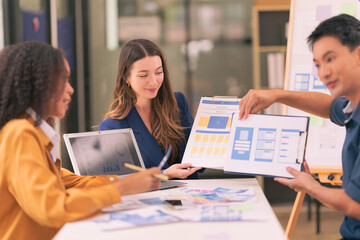 Group of business people designing product that represents the result of successful teamwork with graphic design working with tablet on desk in office.