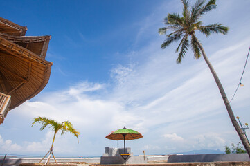 The beauty and comfort of the tropical beach of Lasiana Beach in Kupang City, East Nusa Tenggara, Indonesia. With umbrellas, coconut trees and sunny weather.