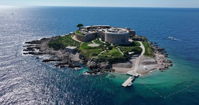 Drone flyover orbit establishing of Mamula Island with surrounding turquoise water and historic structure visible