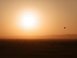Sunrise over a desert landscape with a hot air balloon.