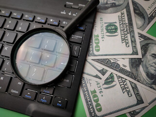 Closeup magnifying glasd,banknote and keyboard business online concept