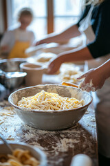 A bright kitchen with a bowl of fresh pasta in the center. A mother and father are rolling out dough while the kids prepare a sauce