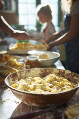 A bright kitchen with a bowl of fresh pasta in the center. A mother and father are rolling out dough while the kids prepare a sauce