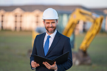 Worker in suit and helmet. Investor civil engineer, construction manager. Construction building developer at a construction site. Successful architect. Handsome hispanic builder man in suit.