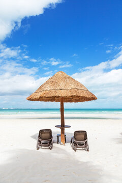 Sunshade and lounge chairs on sandy beach in the Caribbean