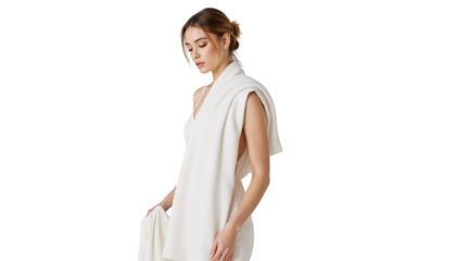 Stylish woman in flowing white dress posing elegantly against a textured wall backdrop