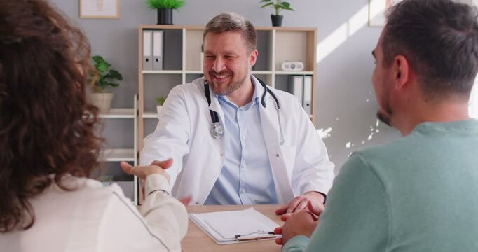 Happy couple visiting doctor and having consultancy in medical office, make hand shake gesture as sign of treatment agreement, planning pregnancy together. Medical specialist giving advice