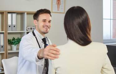 Portrait of smiling friendly male doctor therapist supporting his female patient in office....