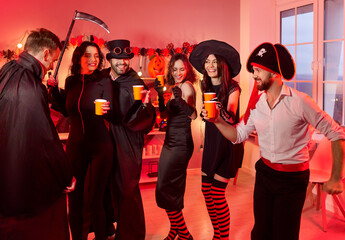 Happy young people group in carnival costumes dancing together celebrating Halloween party at home....