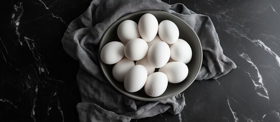 Bowl of fresh white eggs on dark marble.