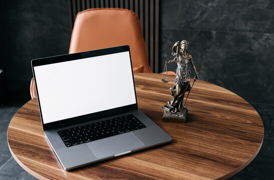 Lawyer's office. Statue of justice with scales and a laptop in a modern office cubicle. Concept of legal law, counseling and concept of justice.