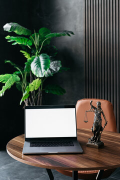 Lawyer's office. Statue of justice with scales and a white screen laptop in a modern office cubicle. Layout for advertising. Concept of legal law.