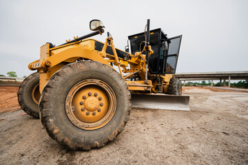 A Road Grader in Construction Site Yellow Grader Digging Soil in Road Construction Site Powerful Construction Machinery for Ground Leveling and Digging Soil Grader for Gravel Road, Dust and Mud