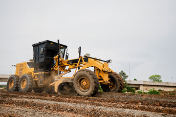 A Road Grader in Construction Site Yellow Grader Digging Soil in Road Construction Site Powerful Construction Machinery for Ground Leveling and Digging Soil Grader for Gravel Road, Dust and Mud