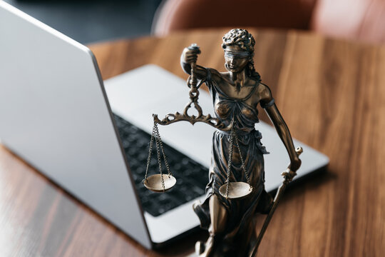 Lawyer's office. Statue of justice with scales and a laptop in a modern office cubicle. Concept of legal law, counseling and concept of justice.