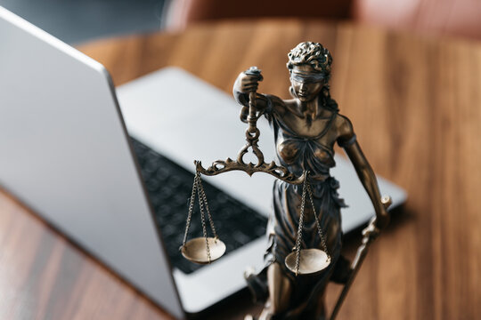 Lawyer's office. Statue of justice with scales and a laptop in a modern office cubicle. Concept of legal law, counseling and concept of justice.