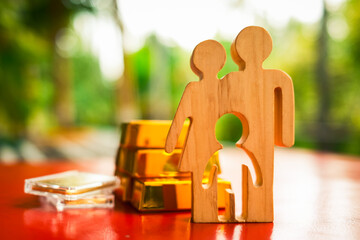 Family model of parents and children standing next to a model of gold and coins collected, the...