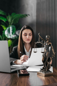 A lawyer or attorney reviews client files, interview transcripts, evidence with a laptop computer in a modern office. Concepts of law and legal services.