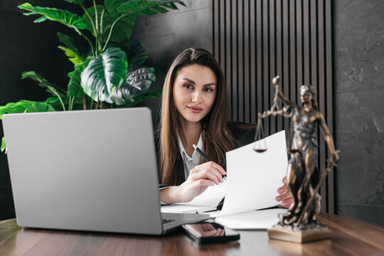 A lawyer or attorney reviews client files, interview transcripts, evidence with a laptop computer in a modern office. Concepts of law and legal services.