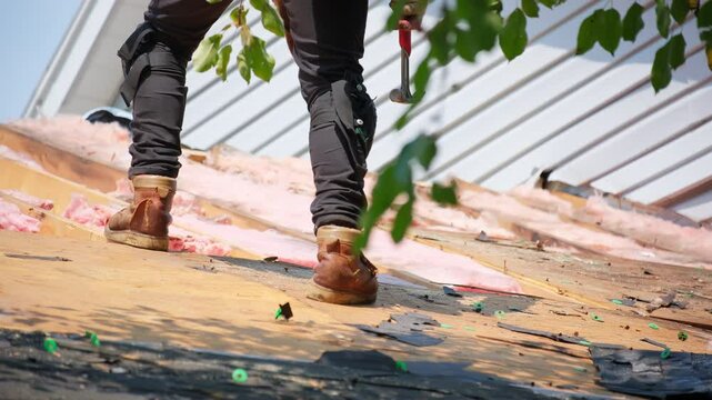 Roofer removes old wood decking of the damaged roof before installing a new covering on an house. Work elements