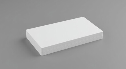 Blank stack of business cards on a gray surface. A stack of white business cards rests on a gray surface, angled slightly to show the layered design.
