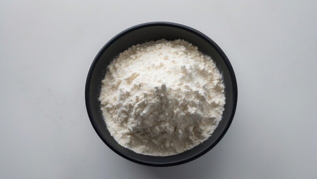 Organic Sorghum Flour contained in a black ceramic bowl viewed from above against a white background