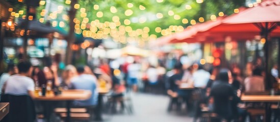 Obraz premium blurred outdoor restaurant ambiance with hanging lights creating a festive and vibrant atmosphere, featuring people dining, providing a sense of community and celebration