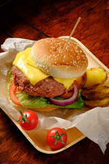 Juicy cheeseburger topped with melted cheese, fresh veggies, and crispy fries on a wooden platter