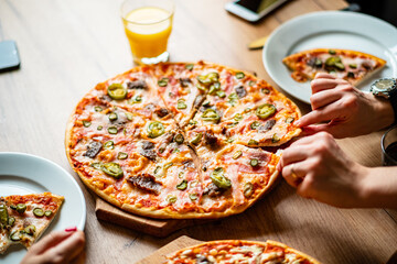 Friends share slices of mouthwatering pizza topped with peppers and savory meats in bright sunlight