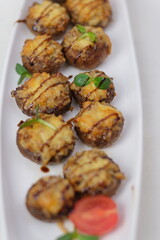 Stuffed mushrooms with cream cheese, bread crumbs and nuts on plate over wooden background. Top view, flat lay