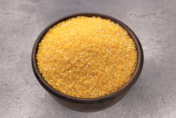 Raw cornmeal in a bowl on a gray tiled table