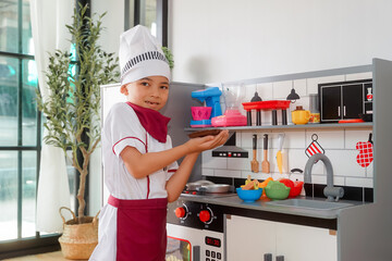 Little boy in chef hat and apron cooking in toy kitchen. Educational toys for young children. Kids play, portrait of Cute little Asian.playing at kitchen at indoor playground