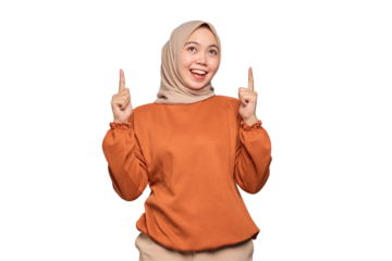 Amazed young Asian woman in orange shirt pointing finger up at copy space isolated on transparent background