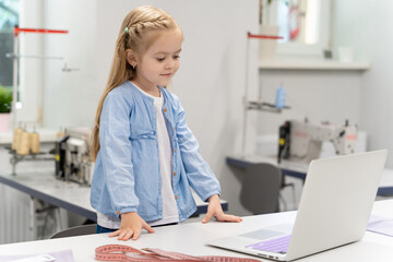 Cute blonde little girl watching something on a laptop