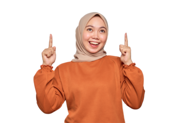 Amazed young Asian woman in orange shirt pointing finger up at copy space isolated on transparent background