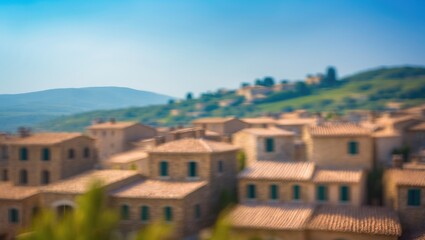 Obraz premium Scenic village landscape featuring defocused stone buildings and verdant hills under a bright summer sky