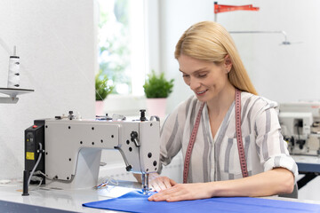 Blonde long-haired caucasian woman at the sewing machine