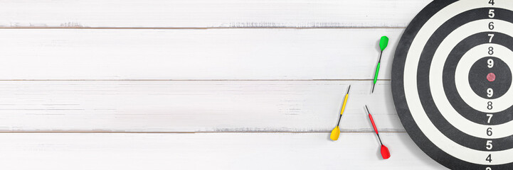 Dartboard with Three Missed Darts on White Wooden Background Symbolizing Challenges and Goals