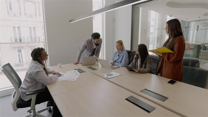 Diverse team of professionals is engaged in a productive meeting in a modern office, collaborating effectively using a laptop to brainstorm innovative strategies for future growth and success