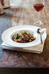 A white bowl of gumbo on wooden table vertical