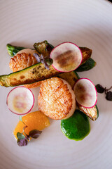 Scallop dish plated with vegetables