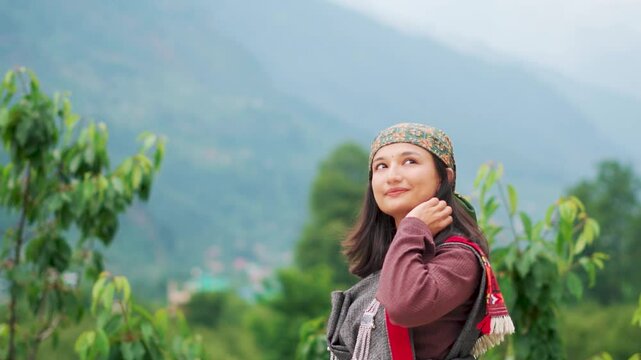 Portrait of young Indian woman wearing traditional Himachali dress and standing against Himalaya mountains in Kullu, Himachal Pradesh, India. Ancient Culture of Kullu and manali. 