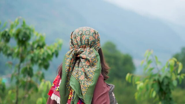 Rear view of Indian girl wearing traditional Himachali headscarf and looking at mountains in Manali, Himachal Pradesh, India. Indian ethnicity woman.