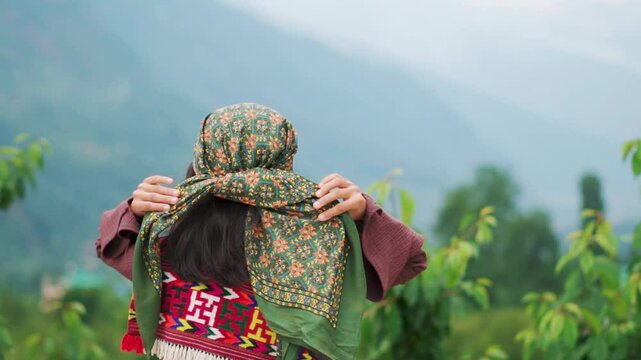 Young woman wearing traditional Himachali costume and looking at mountains in Manali, Himachal Pradesh, India. Real people from rural India. 