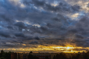 Obraz premium Cloudy orange blue sunset over dark silhouettes of city building