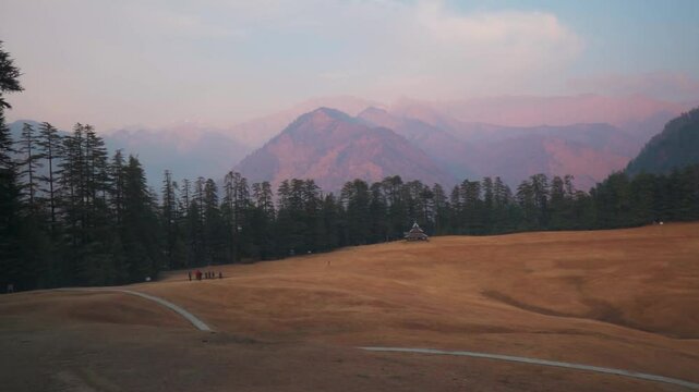 Scenic view of Shangarh meadows surrounded by Pine Trees and Himalaya mountains in Sainj Valley, Himachal Pradesh, India. Celestial meadows and Katkuni style wooden temple.  Mountains landscape.