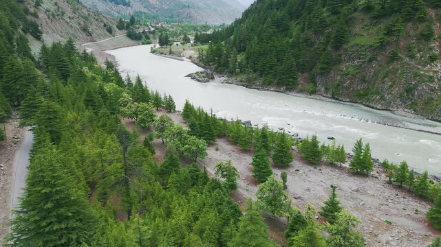 4K Aerial shot of summer landscape of Indian Himalayas. Chenab river flowing in Lahaul Valley and pine trees on river side. Indus river. Travel and holidays concept.