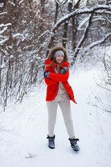 A young girl, blonde, in a sweater, a hat and an orange jacket, against the backdrop of the winter landscape. Snow and frost, the concept of Christmas.