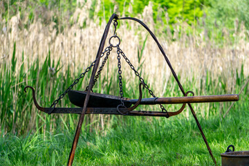 traditional cast iron cooking grate suspended on a tripod, with adjustable hooks and chains for...
